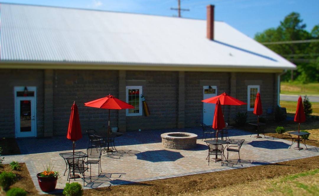 Paver patio with a fire pit and red umbrellas outside a winery