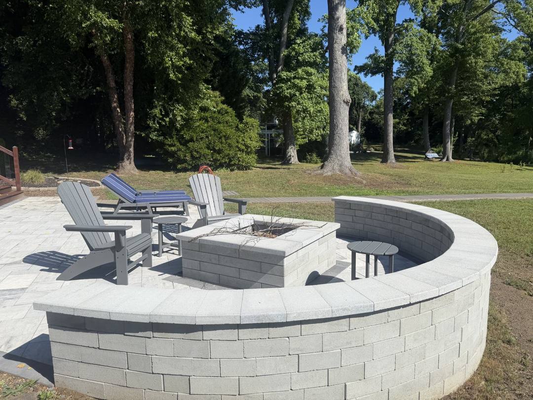 Fire pit and curved seat wall on a gray paver patio with Adirondack chairs