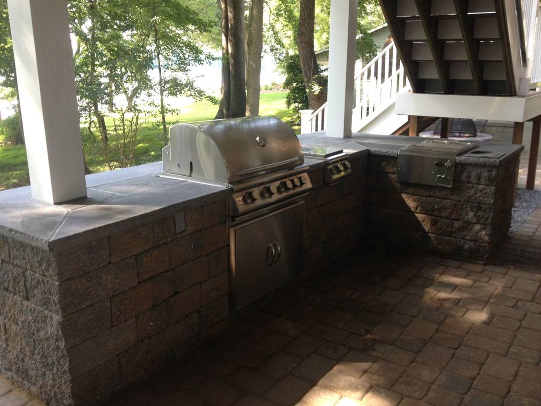 Built-in stainless grill island with stone veneer under a deck