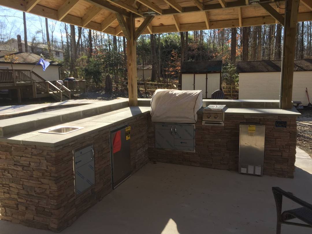 Stone-veneer grill island under a timber pavilion