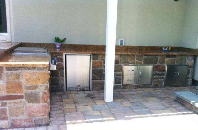 Stone-veneer outdoor kitchen with a built-in refrigerator and drawers