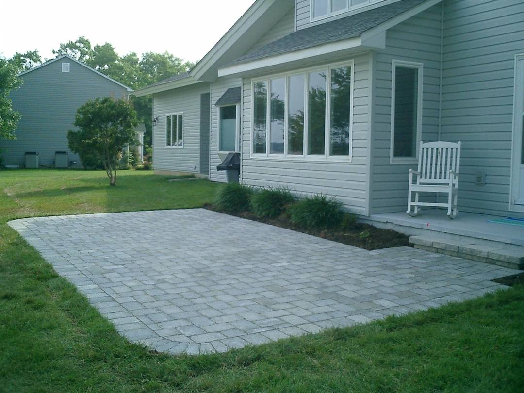 Gray paver patio with a soldier-course border beside the lawn