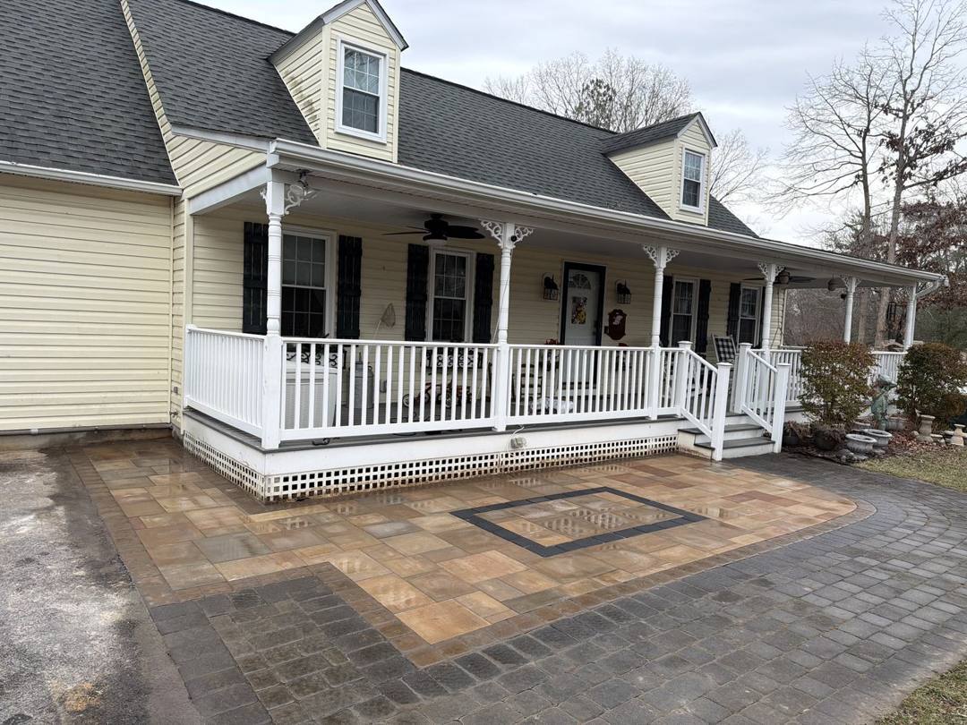 Paver front patio with a border inlay in front of a farmhouse porch