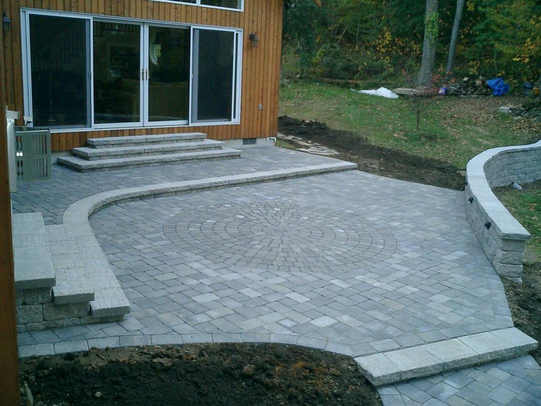 Curved paver patio with steps and a circle inlay at a back door