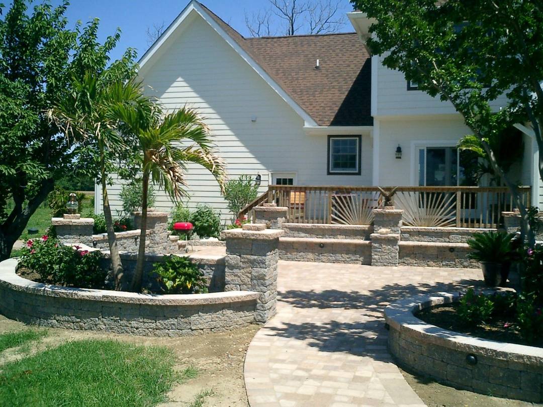 Backyard paver patio with palms, seat walls, and garden beds