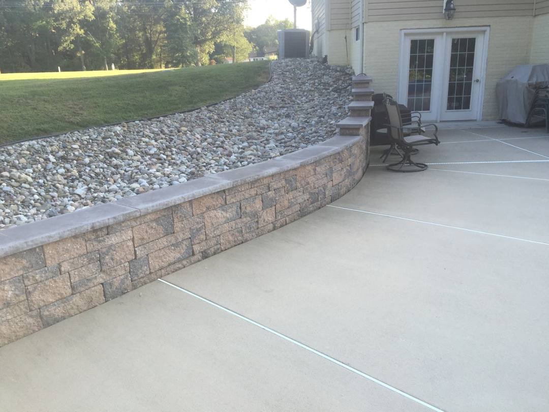 Block retaining wall holding back a gravel slope beside a patio