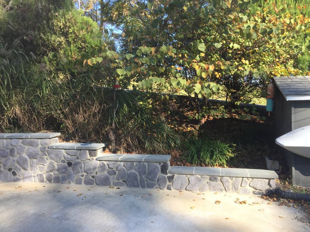 Stone-face retaining wall with a capped top at the patio edge