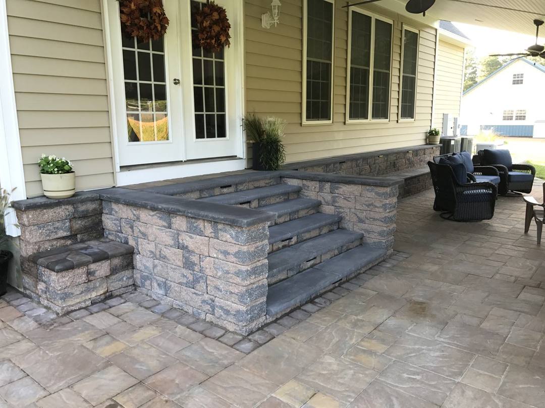 Stone-veneer steps from a covered porch down to a paver patio