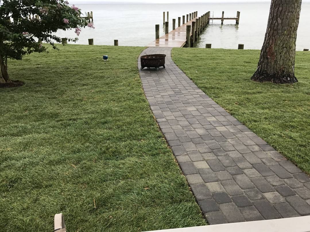 Paver walkway across the lawn to a pier