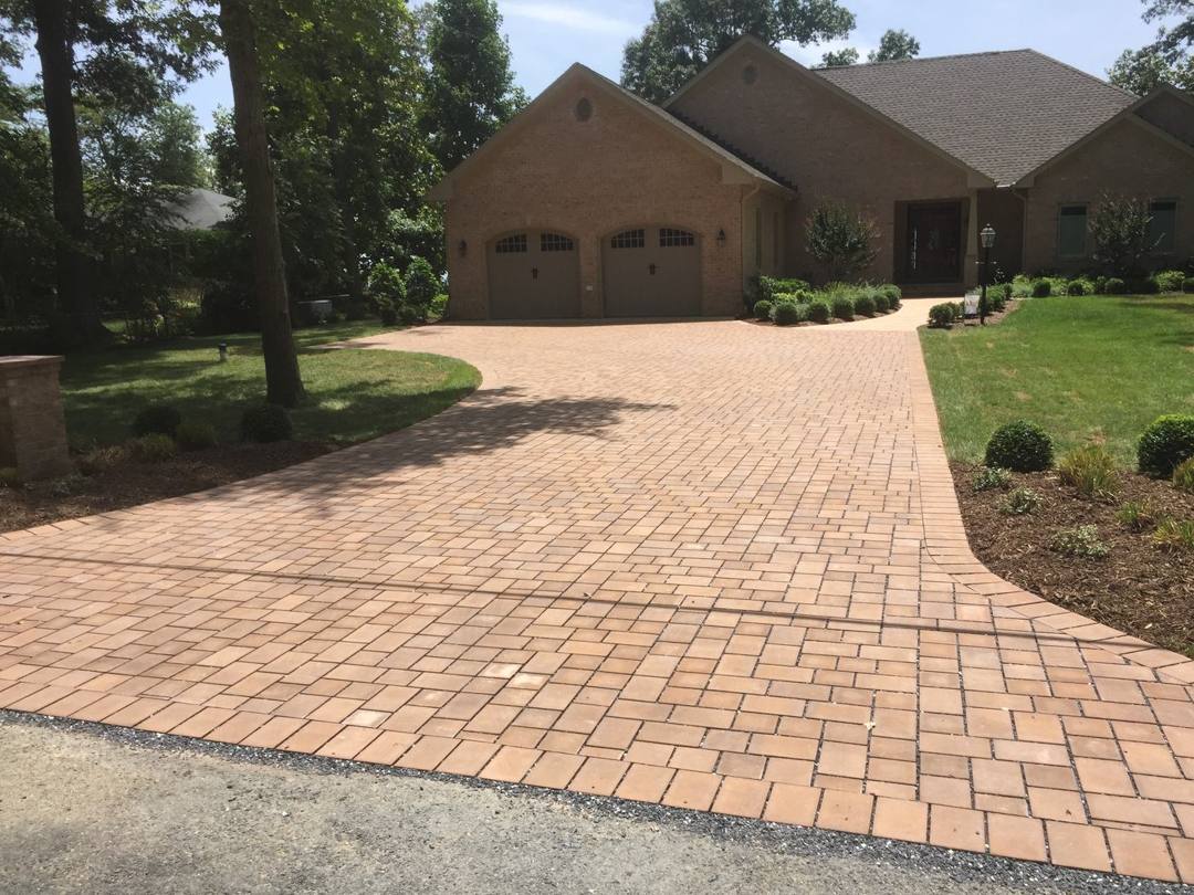 Red clay paver driveway leading to a two-car garage